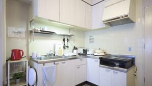 A compact kitchen with white cabinets, a stainless steel countertop, a red kettle, and a coffee machine. - Mezon Etowaru #706 (Nagoya)