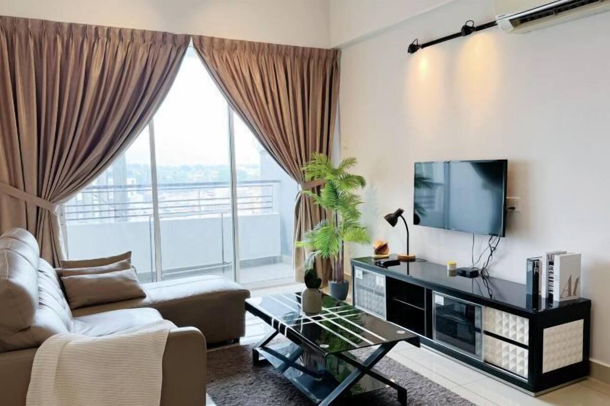 A modern living room with a sofa, a coffee table, a TV, and a plant.