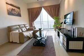 A living room with a sofa, a glass coffee table, a TV, and a large window with curtains. - IPOH The Majestic Imperial Air-Con 6 PAX SUITE (Ipoh)