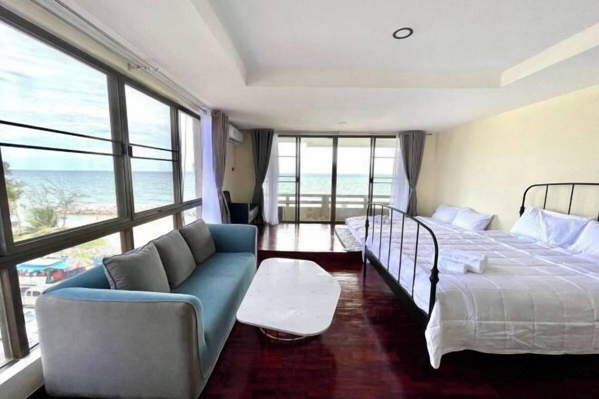 Una camera d'albergo con un'ampia finestra, un letto, un divano e un tavolino.