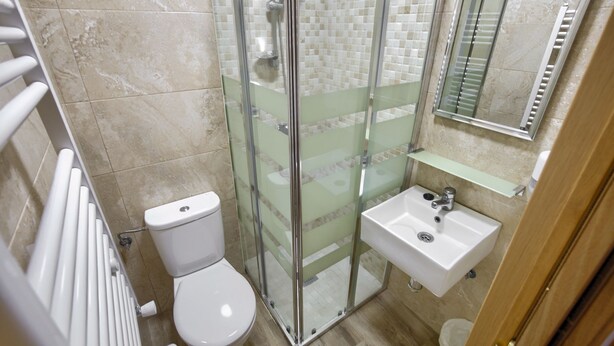 Un baño con ducha de vidrio, inodoro y lavamanos.