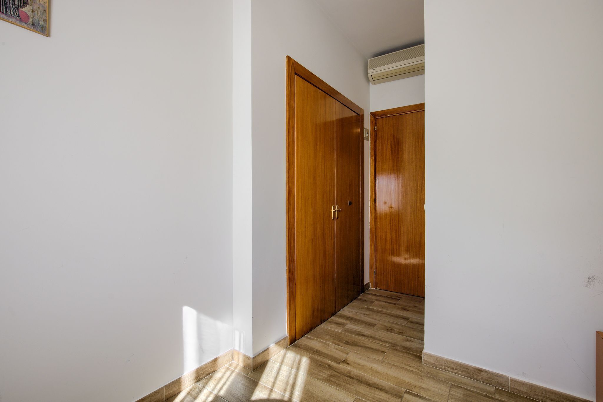 Un couloir avec des portes en bois et un sol carrelé.