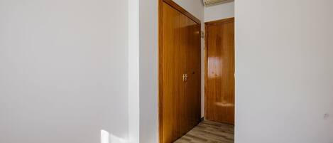 Un couloir avec des portes en bois et un sol carrelé.