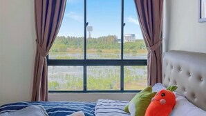 A bedroom with a large window, a bed with striped bedding, and a plush toy on the pillow. - 1 Bedroom Apartment with balcony city view, Melaka Town Centre CBD (Melaka)