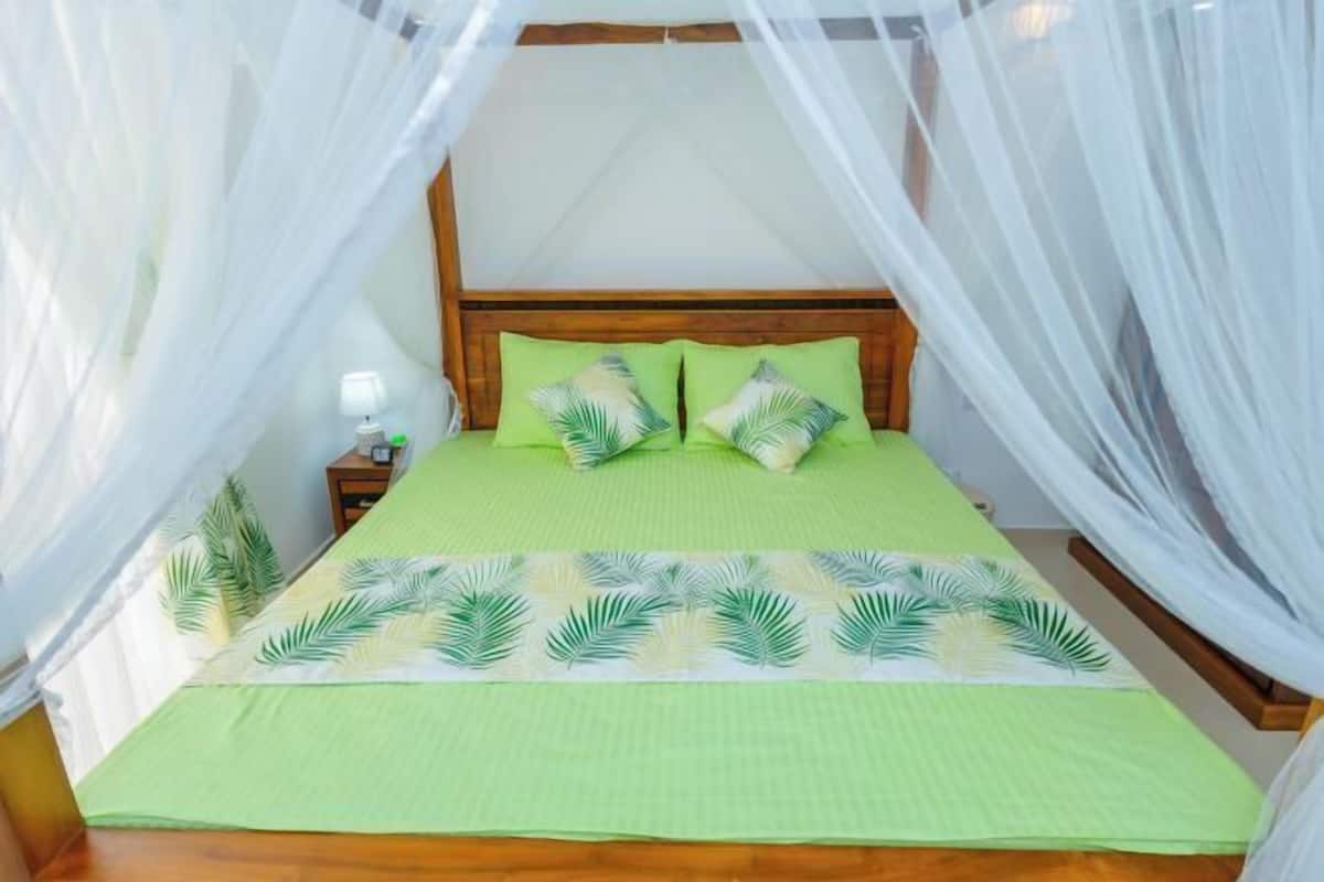 A bed with a canopy, a nightstand, and a lamp.