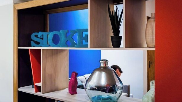 Una habitación con una estantería que contiene objetos decorativos y un gran letrero azul.