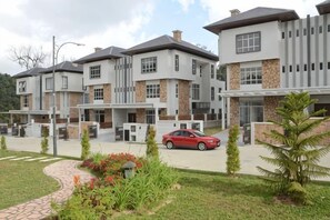 A modern residential building with multiple units, a paved driveway, and a red car parked in front. - Zinnia Residence Tanah Rata (Tanah Rata)