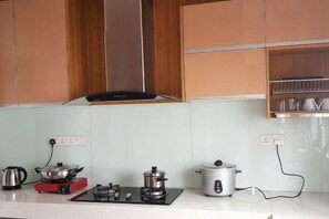 A kitchen with wooden cabinets, a gas stove, a kettle, and a rice cooker. - Zinnia Residence Tanah Rata (Tanah Rata)