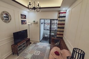 A living room with a television, a patterned rug, a sofa, and a chair. - WHITE ON HOMESTAY CAMERON BY ICOLOR (Tanah Rata)