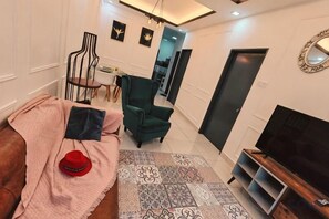 Un salon avec un canapé, un téléviseur et un tapis à motifs.