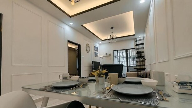 A modern dining area with a glass table, white walls, and a chandelier. - WHITE ON HOMESTAY CAMERON BY ICOLOR (Tanah Rata)