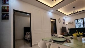 A modern dining area with a glass table, white chairs, and a chandelier. - WHITE ON HOMESTAY CAMERON BY ICOLOR (Tanah Rata)