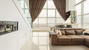Una sala de estar moderna con un sofá seccional grande, una mesa de centro de vidrio y vistas de la ciudad a través de amplias ventanas.