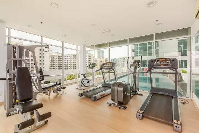 Una palestra con tapis roulant, macchinari per pesi e un'ampia vetrata sulla città.