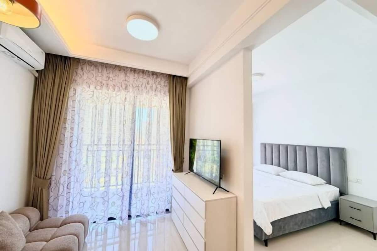 Ein modernes Schlafzimmer mit Bett, Fernseher und Sofa.