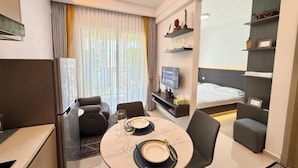 A modern hotel room with a dining area, a sofa, a TV, and a bed. - R Residence (Phnom Penh)