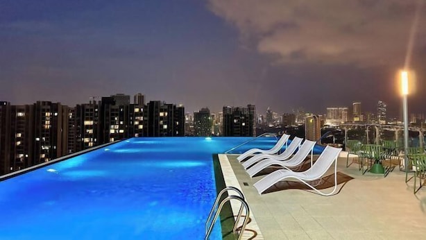 A rooftop pool with lounge chairs and a cityscape view at night. - R Residence (Phnom Penh)