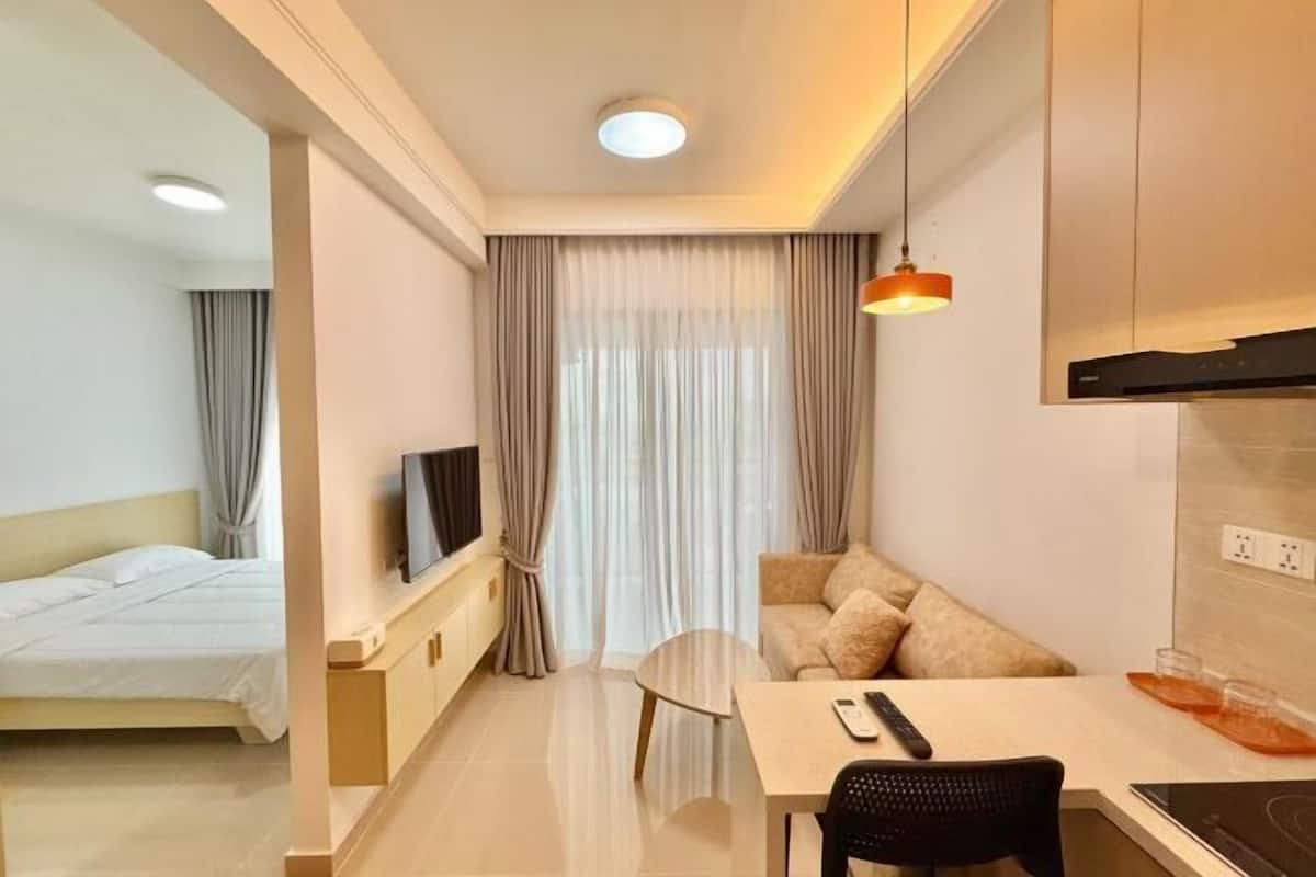 Ein modernes Hotelzimmer mit Bett, Fernseher, Sofa, Esstisch und Küchenzeile.