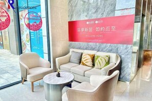 A reception area with a sofa, armchairs, and a coffee table. A red banner with text is visible. - R Residence (Phnom Penh)