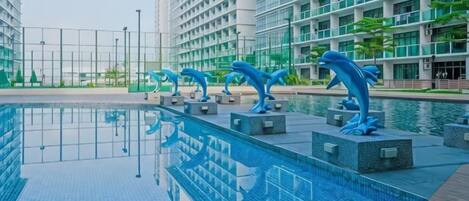 Una piscina con esculturas de delfines, rodeada de edificios modernos.