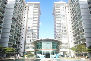 Un moderno edificio de gran altura con una estructura central de vidrio y múltiples balcones.
