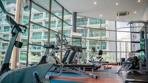 Ein Fitnessstudio mit Laufbändern, Kraftgeräten und großen Fenstern mit Blick auf ein Gebäude.
