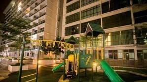 Ein Spielplatz mit Rutschen und Klettergerüsten, umgeben von einem Gebäude mit vielen Fenstern.