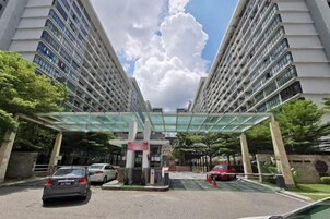 A multi-story building with a covered entrance, cars parked in front, and a clear sky.