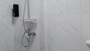 Une salle de bain équipée d’une douche, d’un sèche-mains et d’un téléphone fixé au mur.