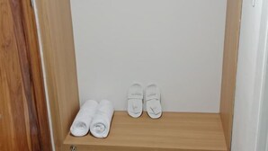Une étagère en bois sur laquelle sont posées deux paires de chaussons blancs et deux serviettes enroulées.