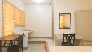 A compact room with a kitchenette, a dining table, two chairs, a mirror, and a wardrobe. - Kababayan Pensione House by RedDoorz (Iloilo City)