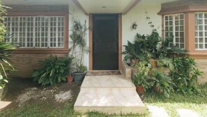 A house with a front door, potted plants, and a small garden area. - Kababayan Pensione House by RedDoorz (Iloilo City)