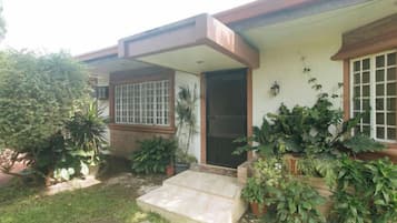 A residential house with a front porch, a door, and potted plants.
