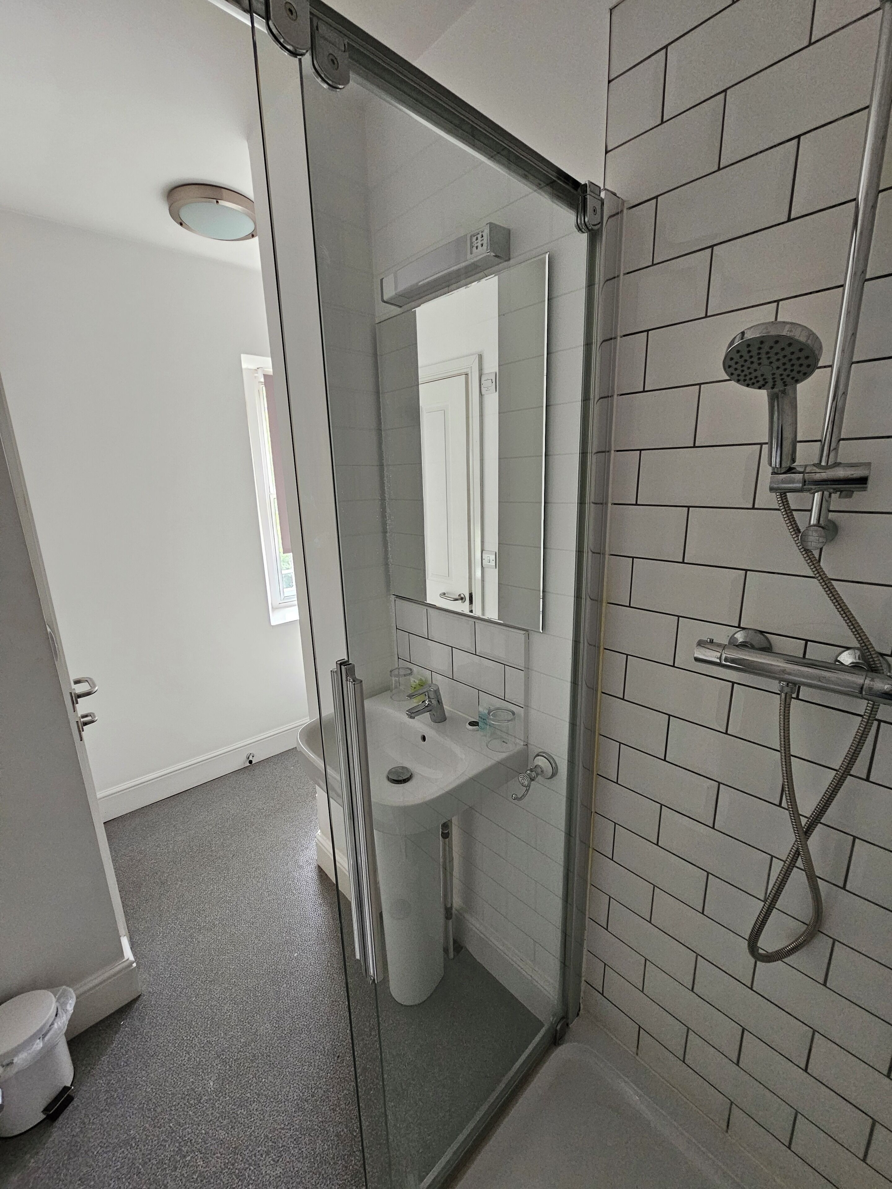 A bathroom with a glass shower enclosure, a sink, and a toilet.