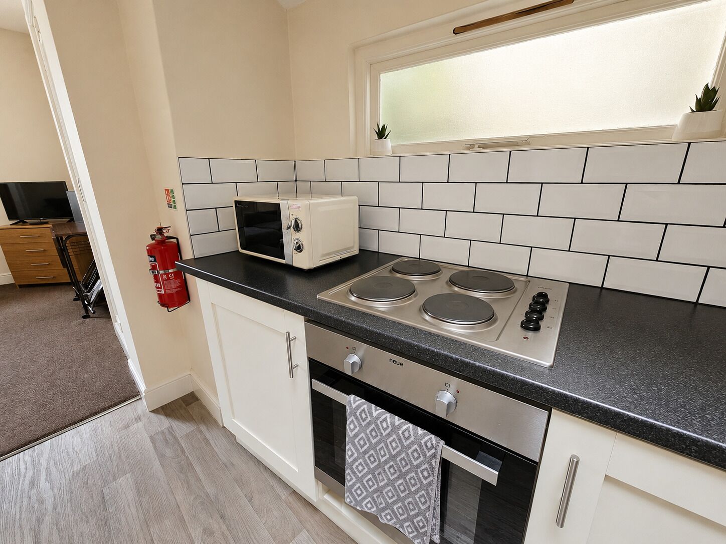 A compact kitchen with a microwave, stove, and white cabinets.