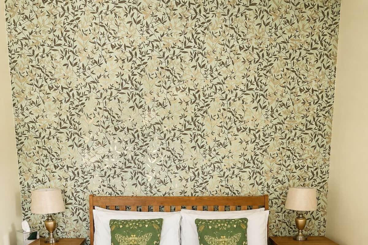 A neatly made bed with two pillows, a bedside table with a lamp, and a sign on the bed.