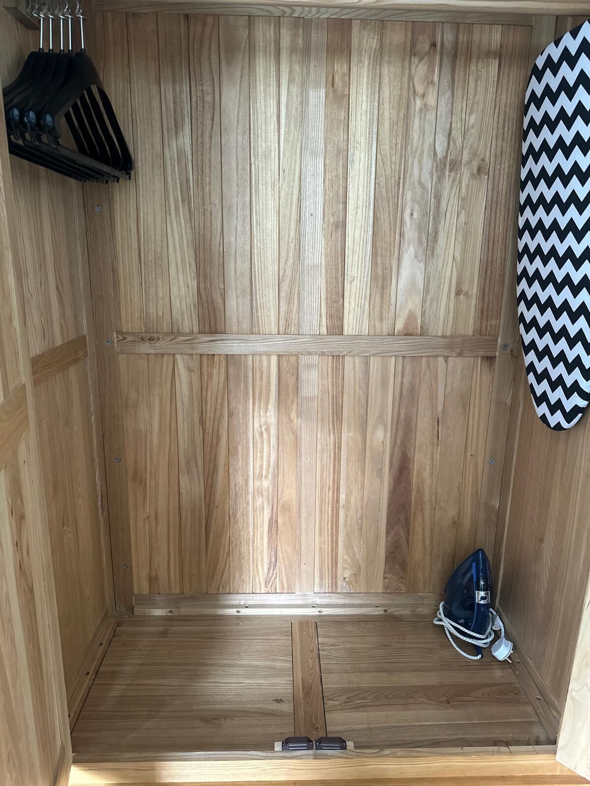 Una habitación de madera con un banco, un calentador fijado a la pared y un objeto con estampado en blanco y negro en zigzag.