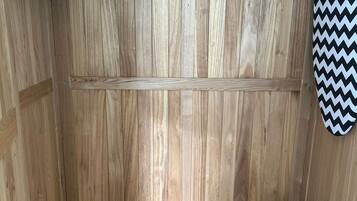 Una habitación de madera con un banco, un calentador fijado a la pared y un objeto con estampado en blanco y negro en zigzag.