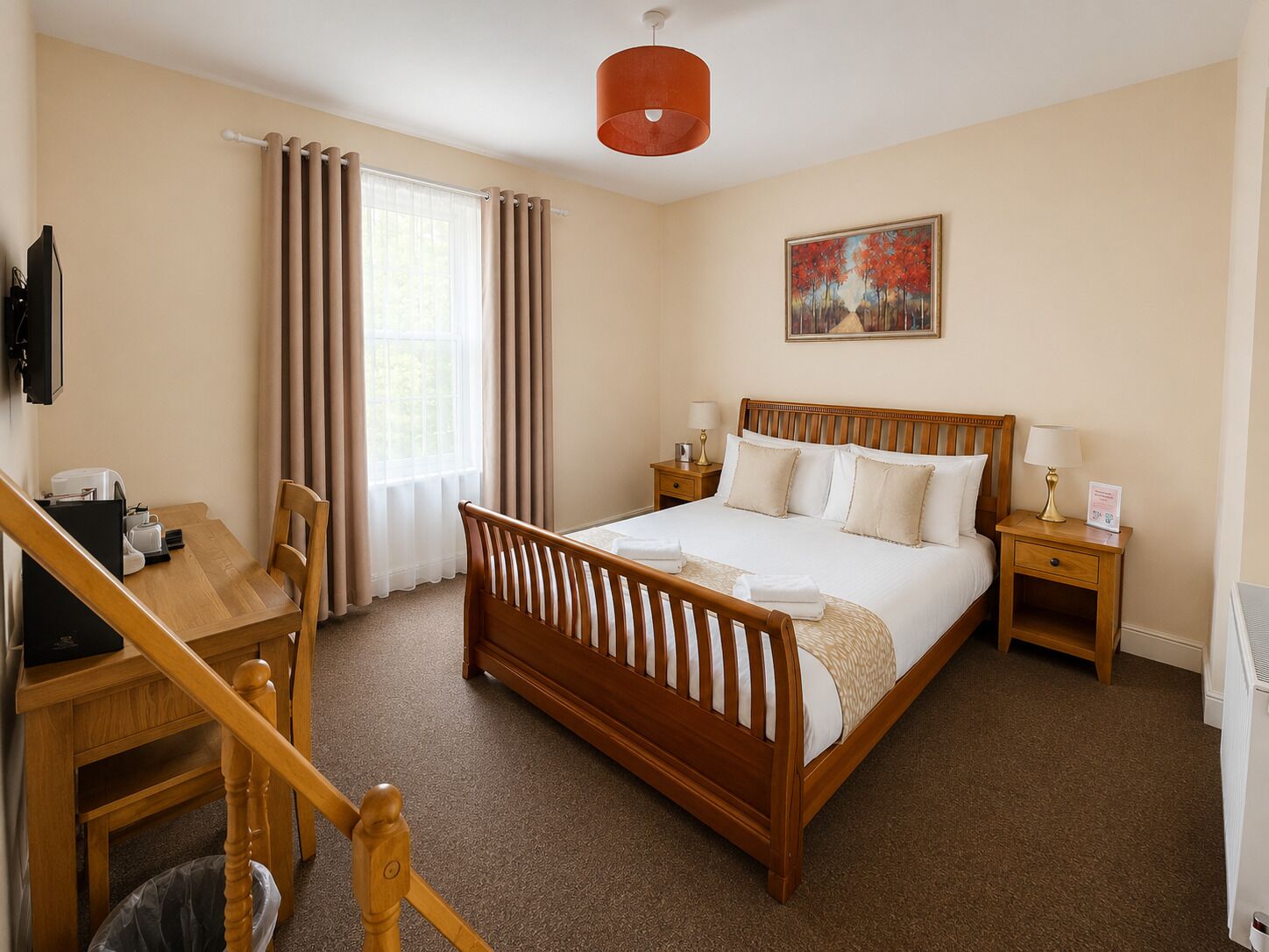 Een hotelkamer met een houten bed, een bureau met stoel, een nachtkastje en een schilderij aan de muur.