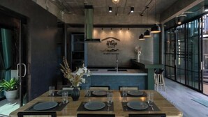 A restaurant with a wooden table set for four, a vase with flowers, and a wall-mounted sign. - Huather Villa & Cafe (Lang Suan)