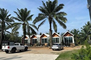 A row of modern, single-story buildings with large windows, surrounded by palm trees. - Huather Villa & Cafe (Lang Suan)