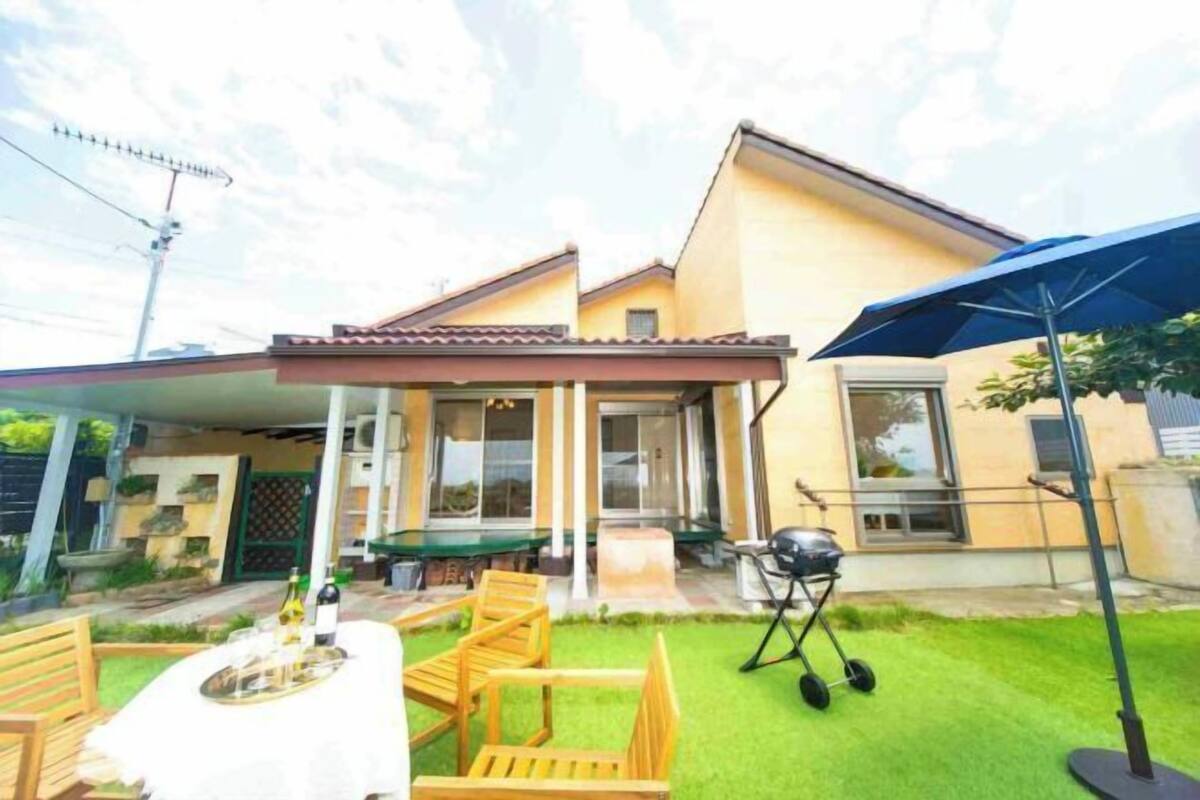Ein Haus mit überdachter Terrasse, Sitzgelegenheiten im Freien und einem Grill.