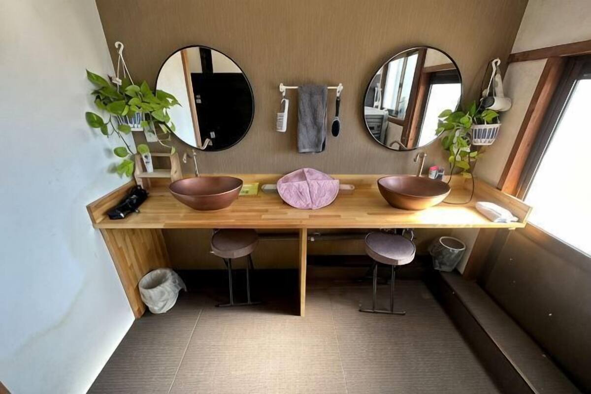 A compact bathroom with two sinks, mirrors, and stools.
