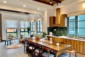 A modern kitchen with a wooden island, large windows, and a dining area with chairs and a table. - 3 bedroom seafront Cherry Villa - Novaworld Phan Thiet (Phan Thiet)