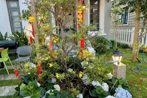 A garden with a tree, white flowers, and a lantern.