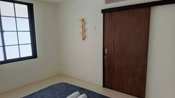 Ein Zimmer mit großem Fenster, einem dunkelbraunen Bett, einem Holzschrank und einer an der Wand befestigten Holzdekoration.