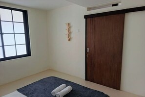 Une pièce dotée d’une grande fenêtre, d’un lit aux couleurs sombres, d’une armoire en bois et d’un élément décoratif en bois fixé au mur.