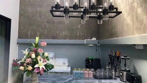 A kitchen with a marble countertop, a flower arrangement, a chandelier, and various kitchen appliances. - My Own House SURAT THANI (Surat Thani)