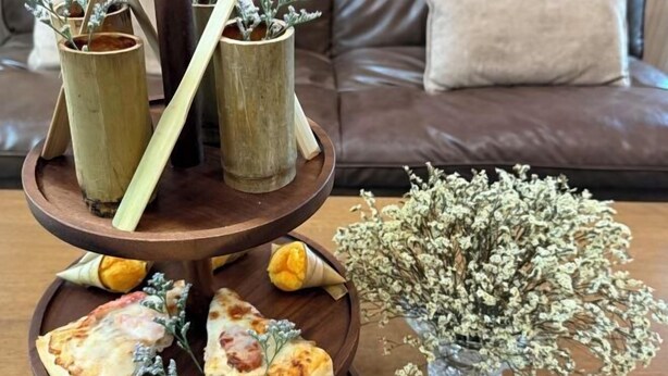 A wooden serving tray with food and a vase of dried flowers on a table. - My Own House SURAT THANI (Surat Thani)
