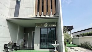A modern building with a flat roof, a large window, and a small outdoor seating area with a table and chairs. - My Own House SURAT THANI (Surat Thani)